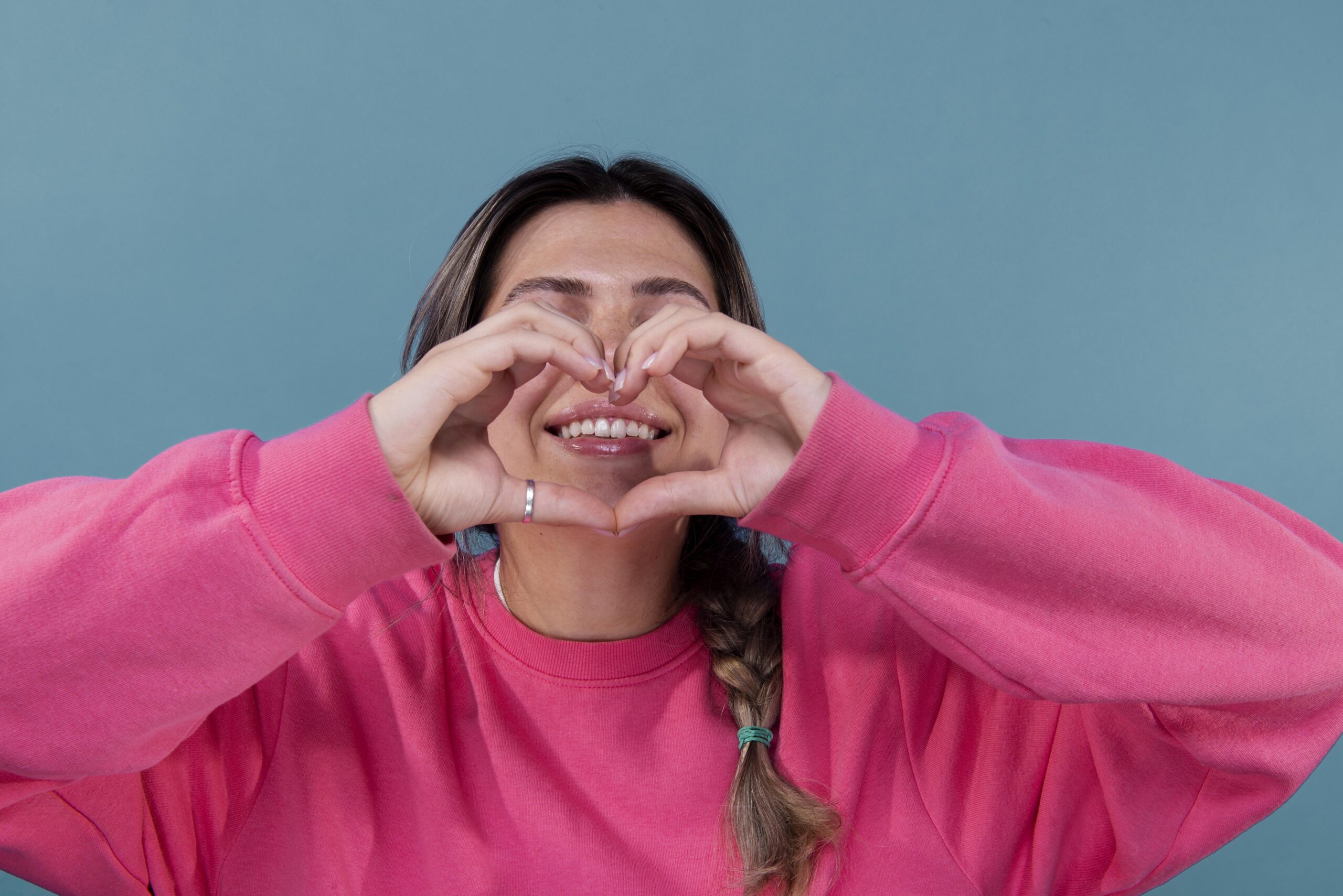 A Woman makes a heart shape symbolizing the connection between Gum Disease and Heart Health in Brentwood.